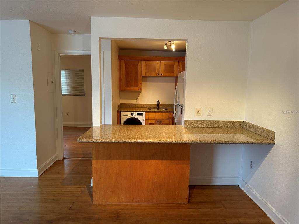 A kitchen with wood cabinets and a granite breakfast bar overlooks a living area — 3914 W NEPTUNE STREET UNIT 29, TAMPA, FL