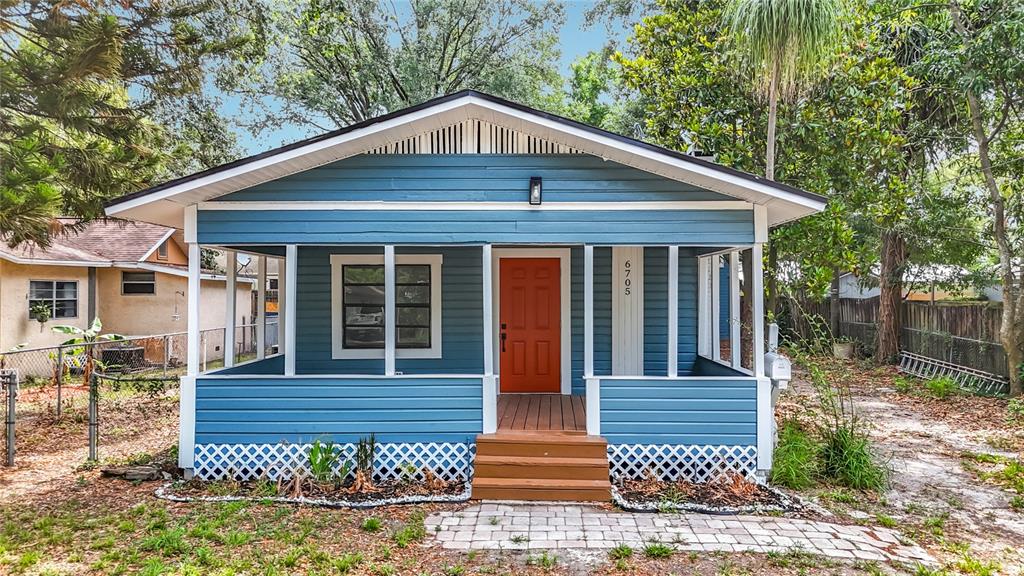A blue house with a front porch, an orange door, and a lattice foundation — 6705 N ELIZABETH STREET, TAMPA, FL