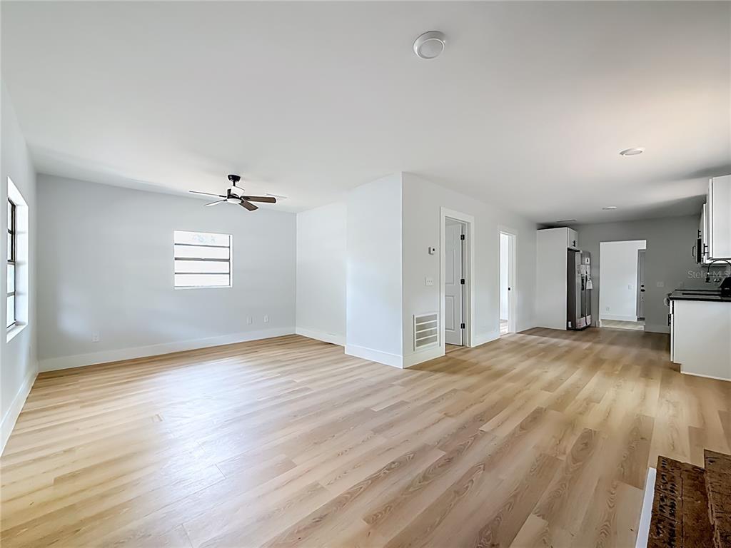 An open-concept living area features light wood-look flooring, white walls, and a ceiling fan — 6705 N ELIZABETH STREET, TAMPA, FL