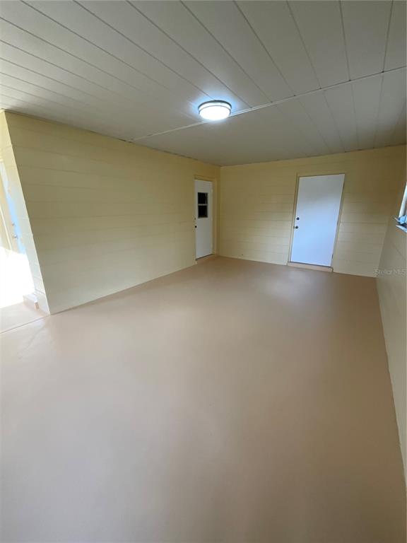 An enclosed porch with light yellow walls, a tan floor, and a single ceiling light — 9359 BAHIA ROAD, OCALA, FL