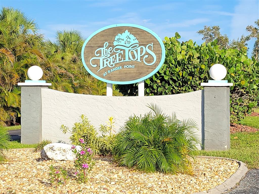 An oval sign for The Treetops at Ranger Point stands above a stucco wall and landscaping — 14277 PALM TERRACE, PORT CHARLOTTE, FL
