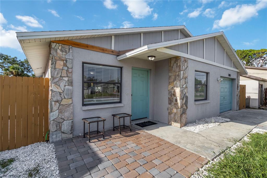 A single-story house with a stone-accented facade, a teal front door, and a paver patio — 1883 MOVA STREET, SARASOTA, FL
