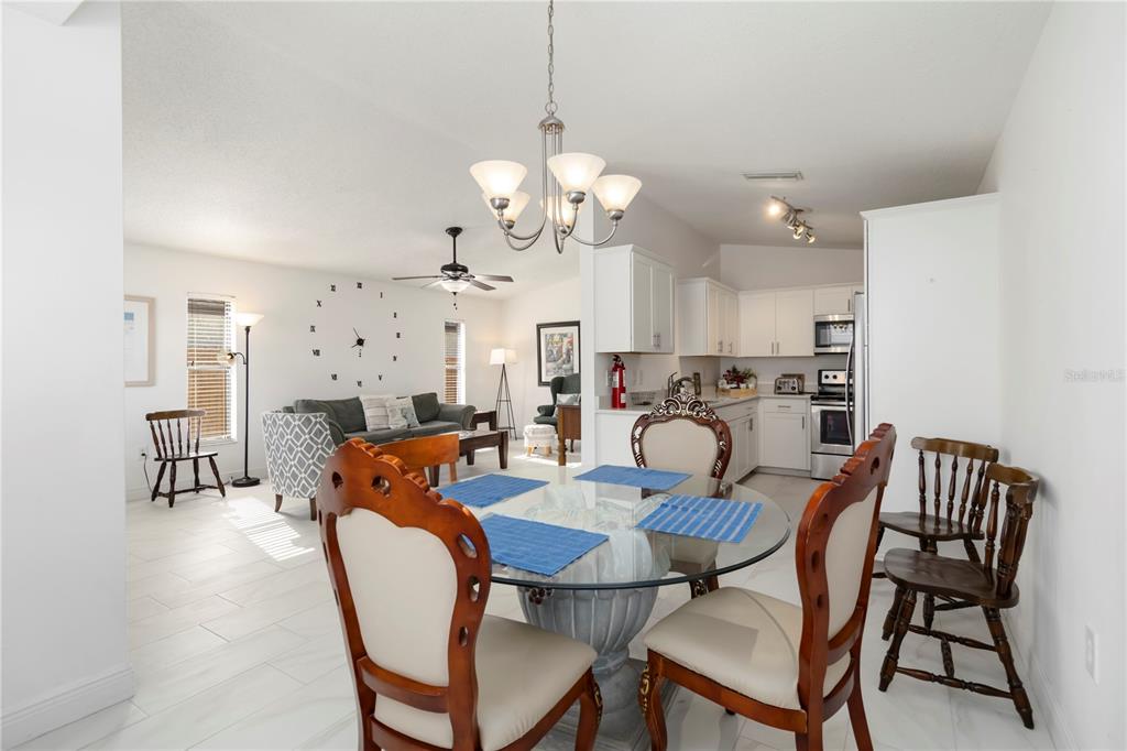 An open-concept dining area and living room feature white tile floors and a glass-topped table — 1883 MOVA STREET, SARASOTA, FL