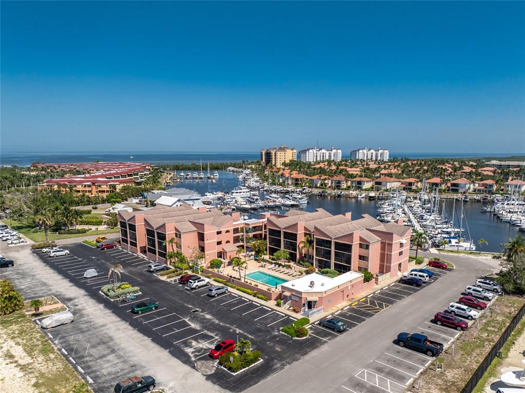 An aerial view shows a pink multi-story apartment complex with a pool and marina — 3160 MATECUMBE KEY ROAD UNIT 238, PUNTA GORDA, FL