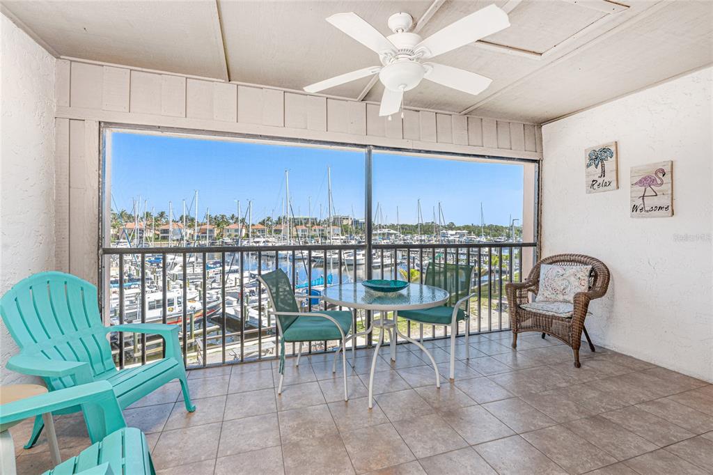 A screened-in balcony with tile flooring overlooks a marina filled with boats — 3160 MATECUMBE KEY ROAD UNIT 238, PUNTA GORDA, FL