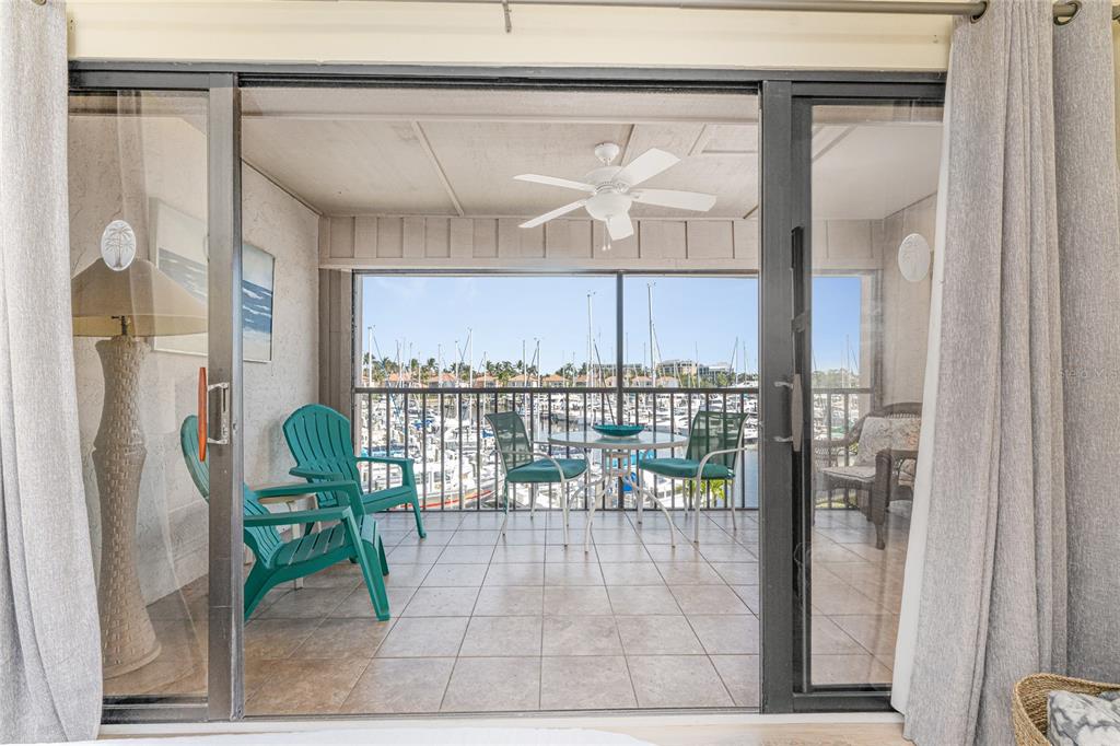 A tiled balcony with patio furniture overlooks a marina through a sliding glass door — 3160 MATECUMBE KEY ROAD UNIT 238, PUNTA GORDA, FL