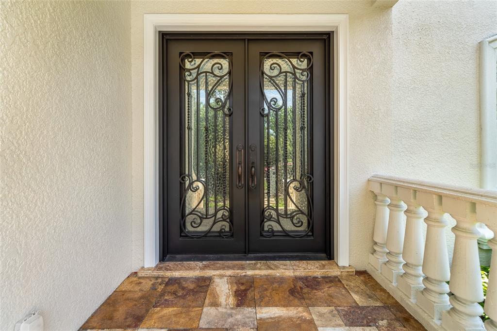 A double front door with decorative iron grilles opens onto a tiled entryway porch — 4802 W BEACHWAY DRIVE, TAMPA, FL