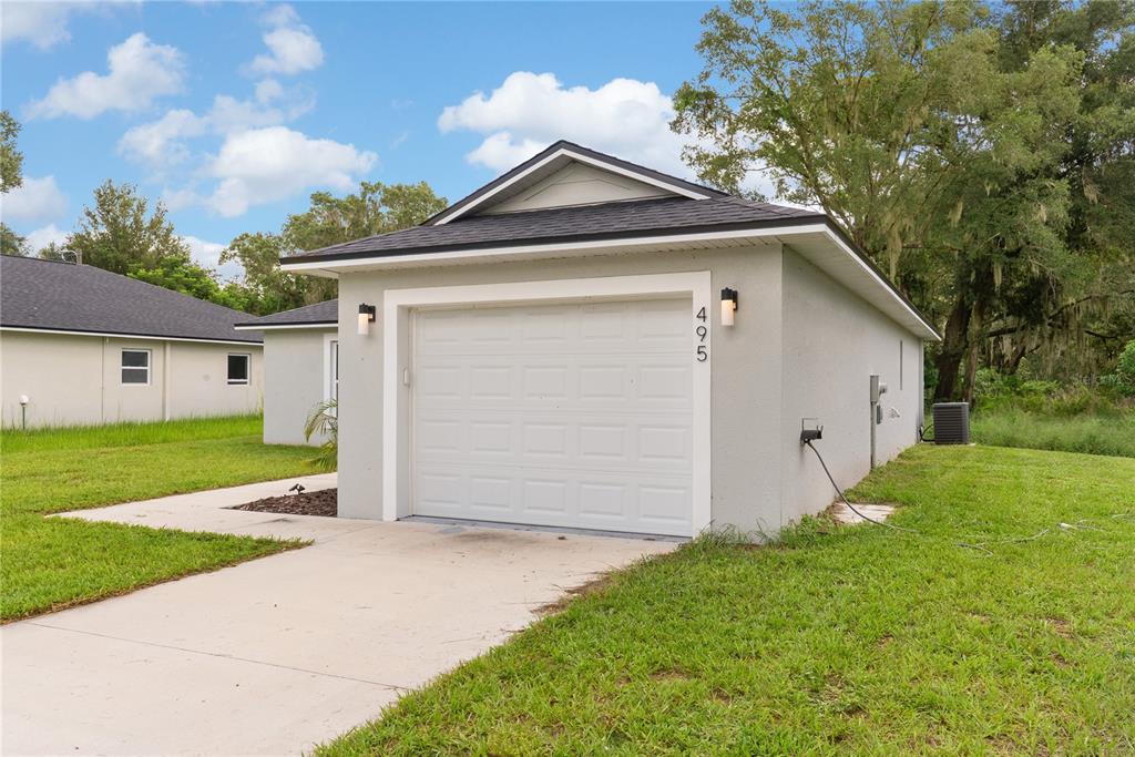A detached, light-gray, single-car garage with a white door and a dark shingled roof — 495 S OAK AVENUE, FORT MEADE, FL