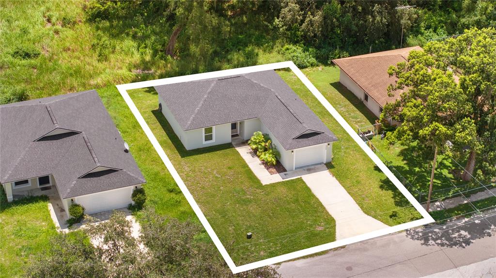 An aerial view shows a single-story house with a gray roof and a concrete driveway — 495 S OAK AVENUE, FORT MEADE, FL