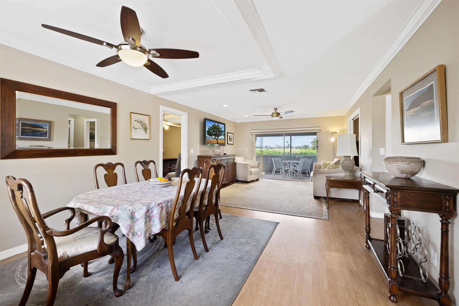 A dining area with a wooden table and chairs sits adjacent to a living room — 13771 Via Aurora, Delray Beach FL 33484, DELRAY BEACH, FL