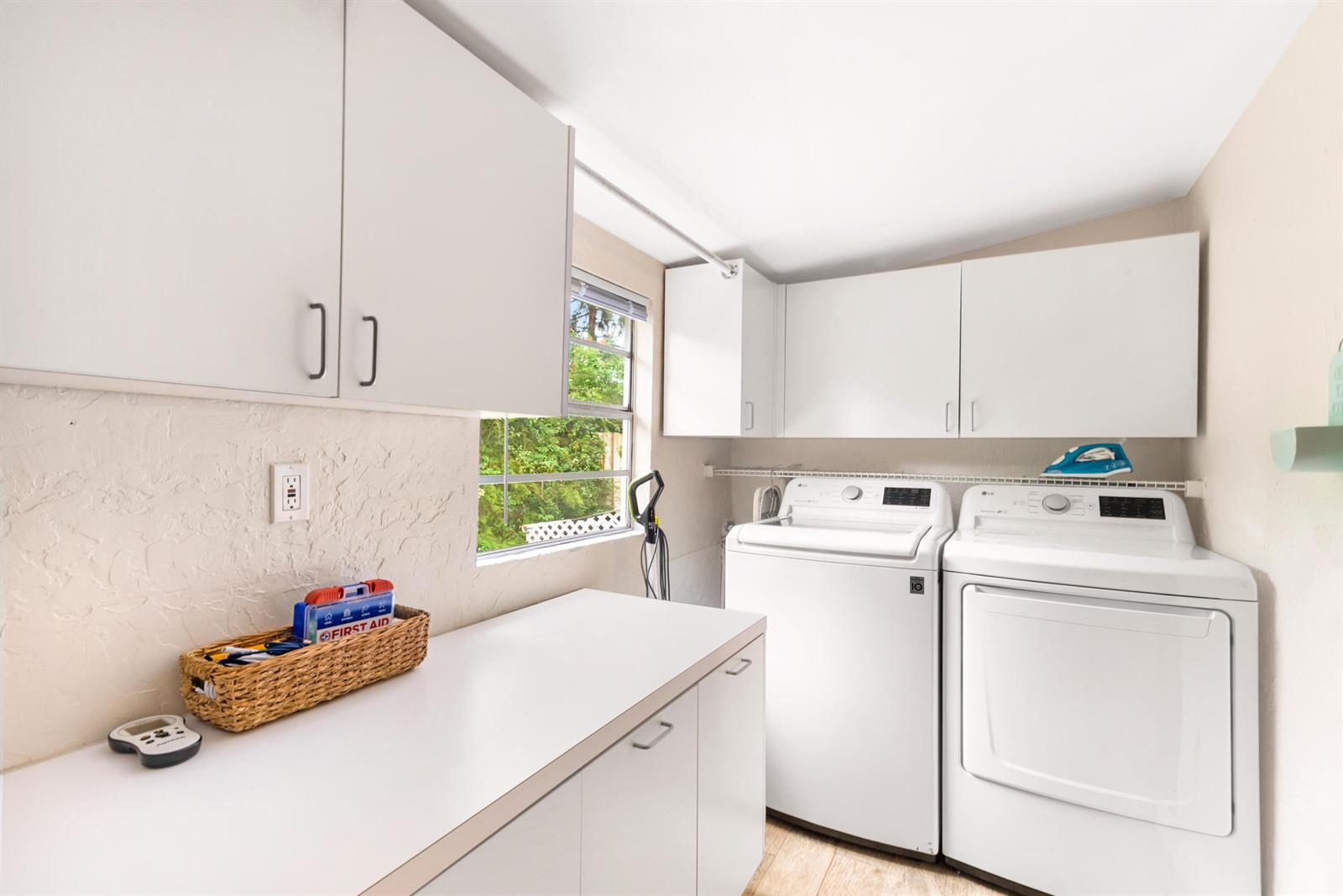 A laundry room features white cabinets, a countertop, and a side-by-side washer and dryer — 303 Lang Road, Cloud Lake FL 33406, CLOUD LAKE, FL
