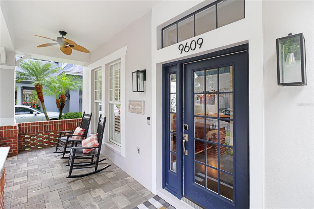 A covered front porch features two rocking chairs, a blue door, and brick accents — 9609 ROYCE DRIVE, TAMPA, FL
