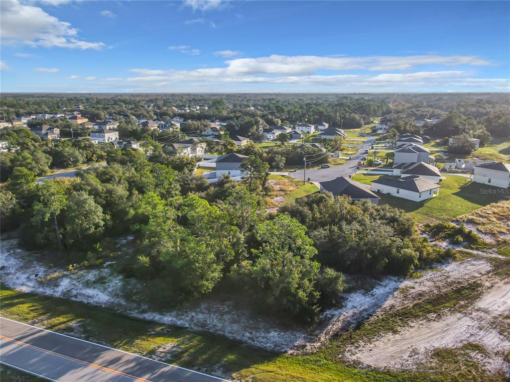An aerial view shows a vacant, wooded lot situated next to a residential neighborhood — 1257 AMAZON LANE, POINCIANA, FL