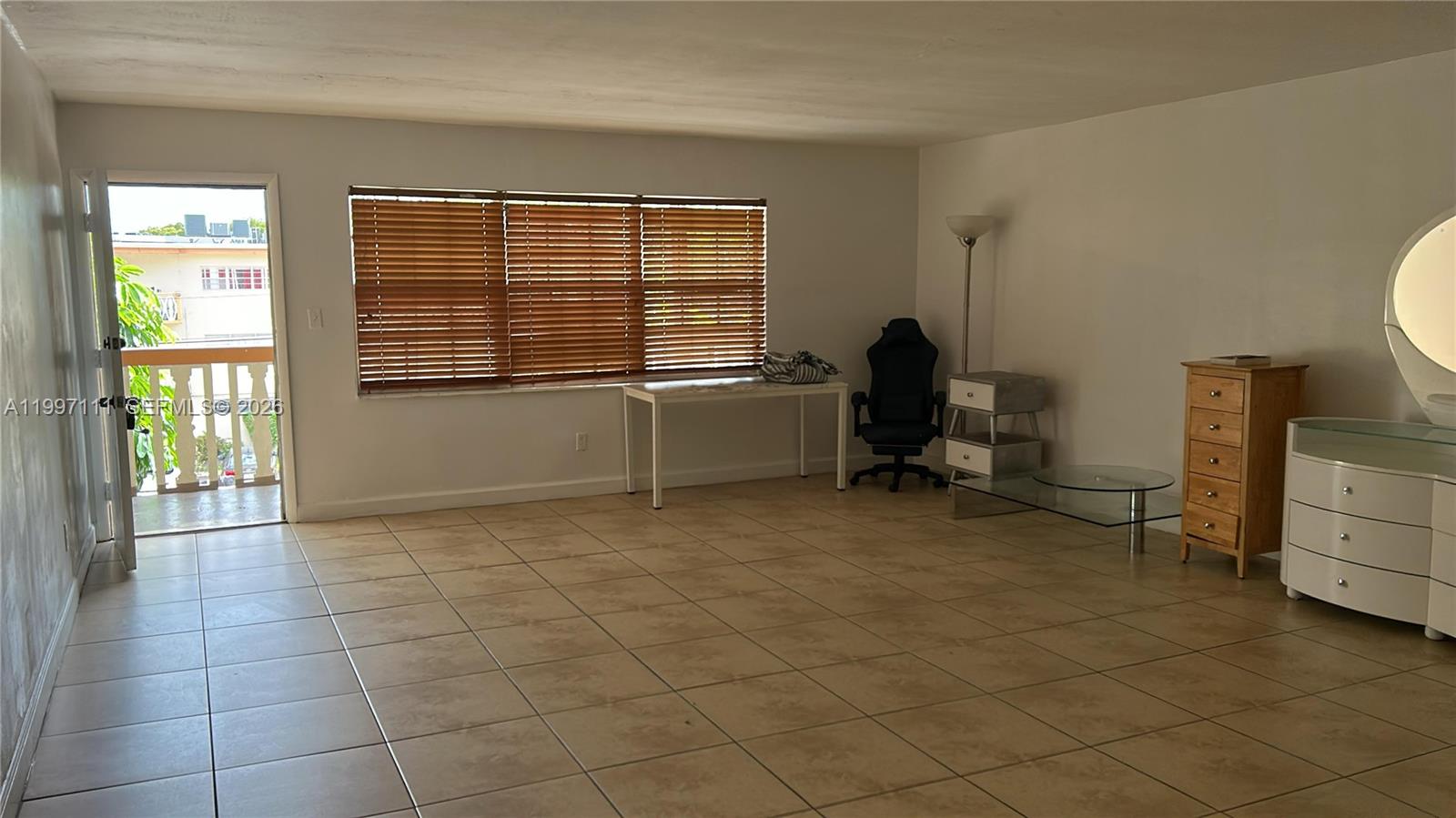 A living room with tile flooring, a large window with blinds, and a balcony door — 1855 NE 121st St # 35, North Miami FL 33181, NORTH MIAMI, FL