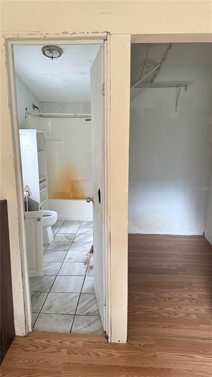 A view through an open doorway shows a bathroom with a tub and tile floor — 6408 WOODSMAN DRIVE, WESLEY CHAPEL, FL
