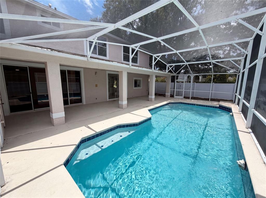 A screened-in patio features a swimming pool with blue tile trim and concrete decking — 2270 BLOSSOMWOOD DRIVE, OVIEDO, FL