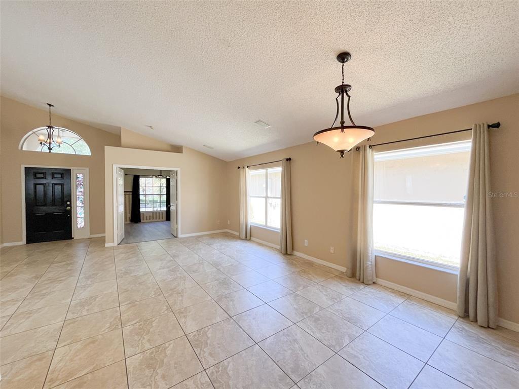 A tiled living room features a vaulted ceiling, a chandelier, and a black front door — 4397 KING EDWARD DRIVE, ORLANDO, FL