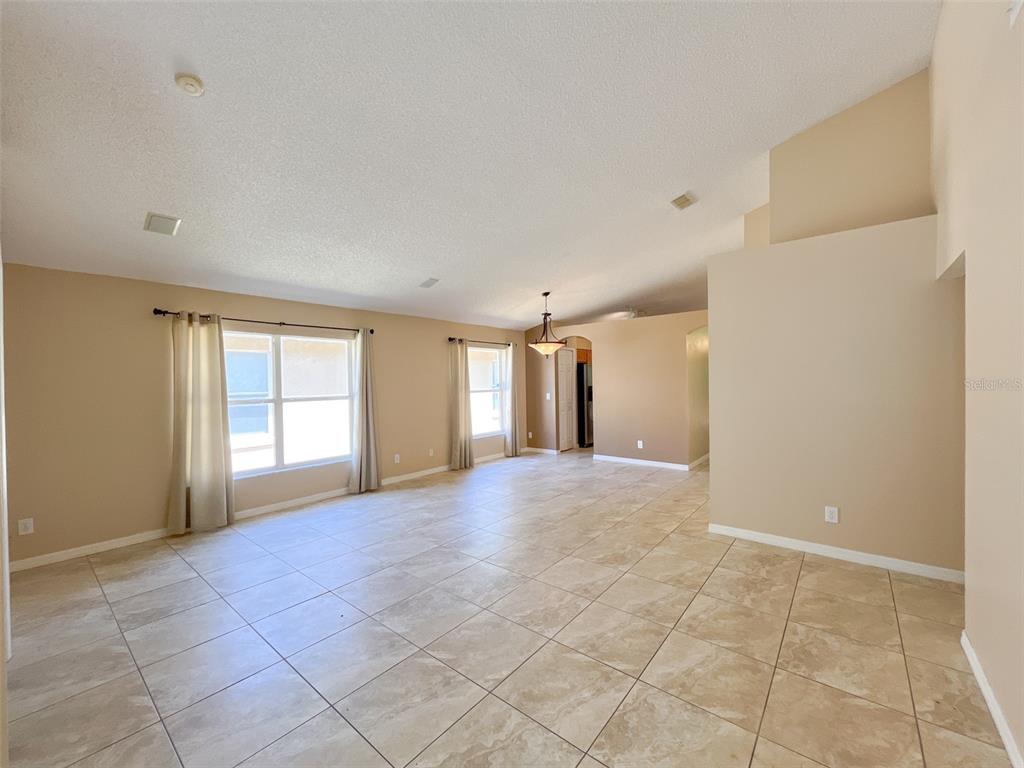 An open-concept living area features beige walls, vaulted ceilings, and light-colored tile flooring — 4397 KING EDWARD DRIVE, ORLANDO, FL