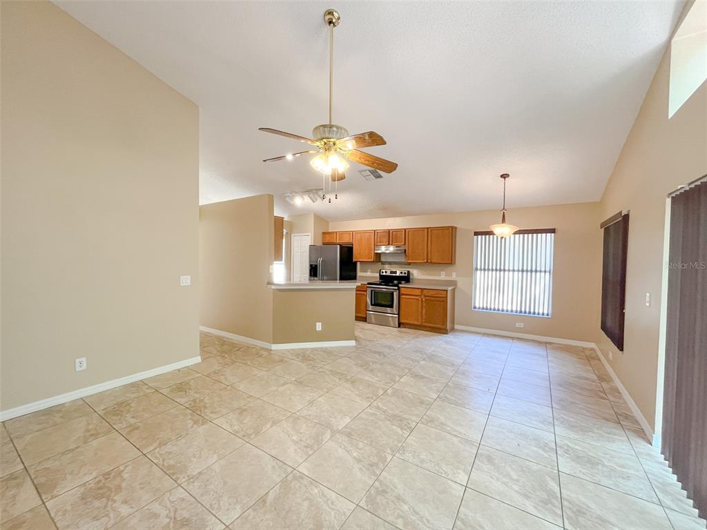 An open-concept kitchen with wood cabinets and tile flooring overlooks a spacious living area — 4397 KING EDWARD DRIVE, ORLANDO, FL