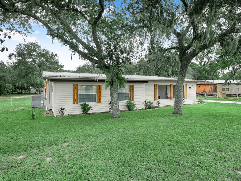 A single-story house with light-colored siding and wooden shutters sits on a grassy lot — 2935 N SILVER SPUR LOOP, LAKE WALES, FL