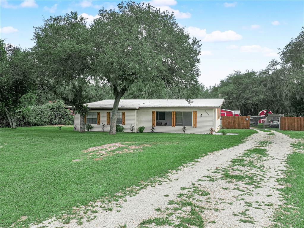 A single-story house with light siding and a metal roof sits on a grassy lot — 2935 N SILVER SPUR LOOP, LAKE WALES, FL