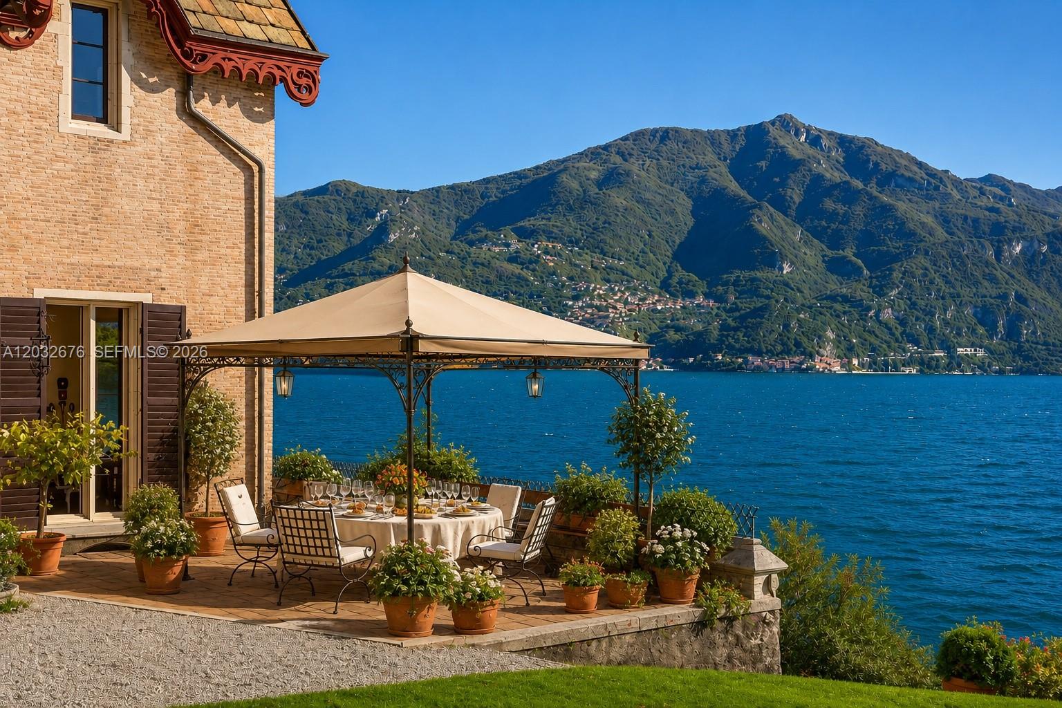 A patio with a dining set and gazebo overlooks a lake and mountains — Lake Como Luxury Real Estate for Sale Max Mlekus, FL