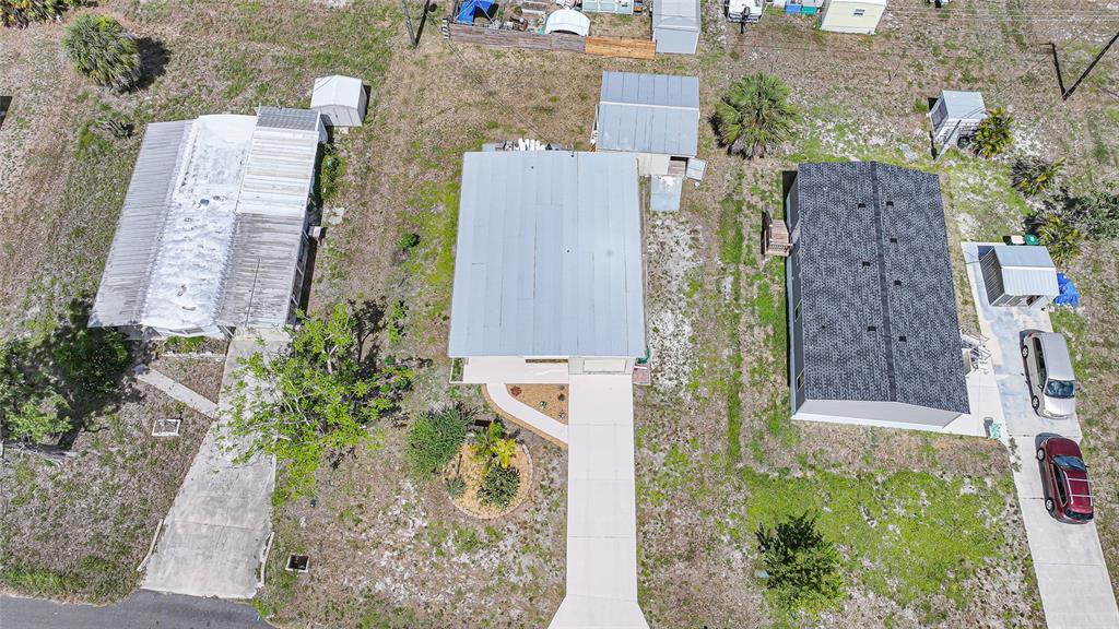 An aerial view shows three houses with driveways, sheds, and sparse landscaping on a grassy lot — 658 VIA CALA, ENGLEWOOD, FL