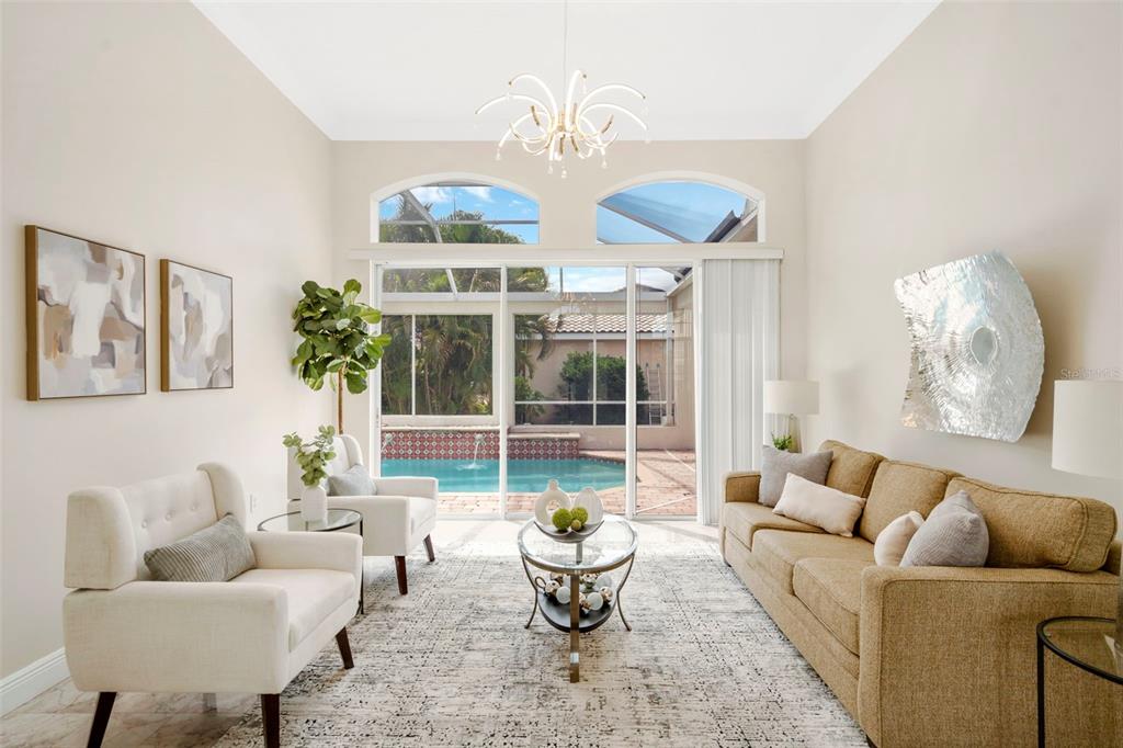 A living room features a tan sofa, two white armchairs, and a view of a pool — 5909 ZAKI LANE, APOLLO BEACH, FL