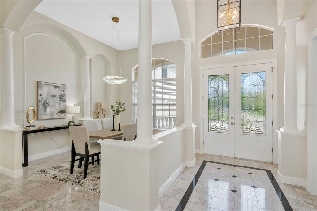 A bright foyer with marble floors leads to an adjacent dining area with white columns — 5909 ZAKI LANE, APOLLO BEACH, FL