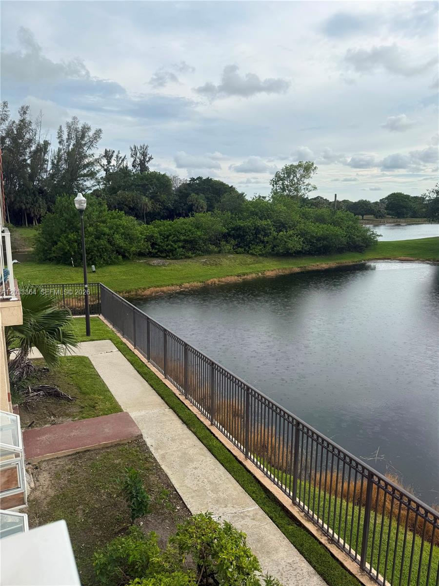 An elevated view shows a metal fence bordering a pond with trees in the background — 3350 N Pinewalk Dr N # 1427, Margate FL 33063, MARGATE, FL