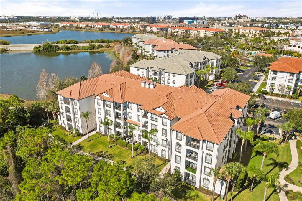 An aerial view shows a multi-story apartment complex with terracotta roofs near a lake — 4024 BREAKVIEW DRIVE UNIT 40304, ORLANDO, FL