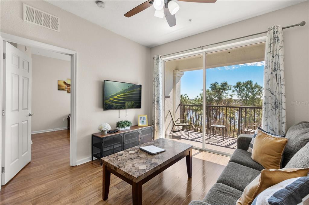 A living room features wood flooring, a marble-topped coffee table, and a balcony with water views — 4024 BREAKVIEW DRIVE UNIT 40304, ORLANDO, FL