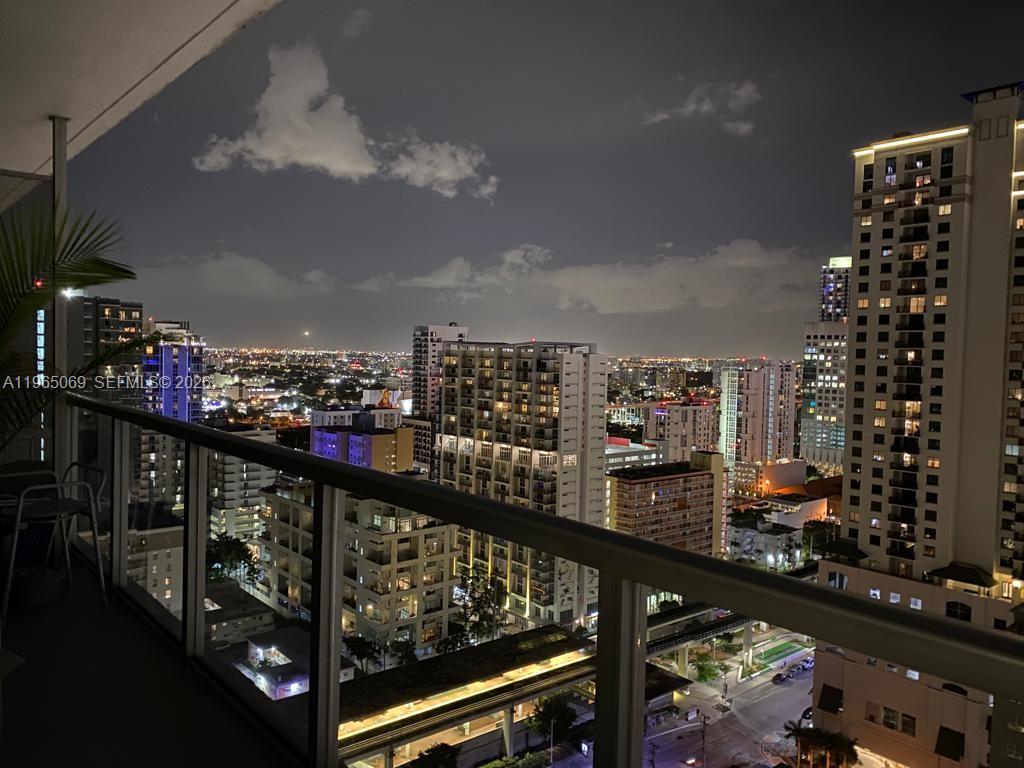 A high-angle night view of a city skyline from a glass-railed balcony — 1111 SW 1st Ave, Miami FL 33130, MIAMI, FL