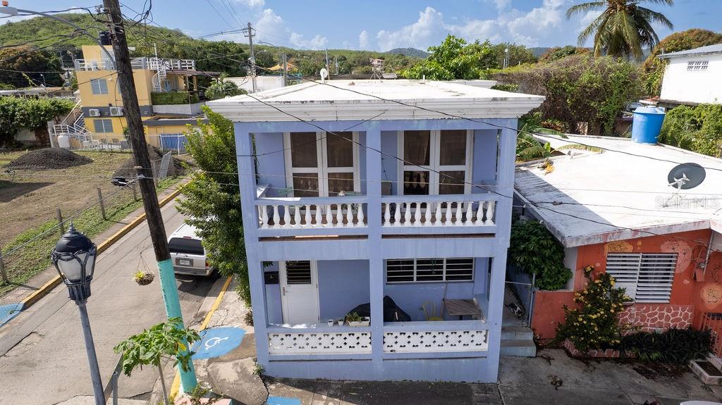 A two-story light blue house with balconies and a flat roof stands along a street — 112 CALLE MUÑOZ RIVERA, VIEQUES, PR