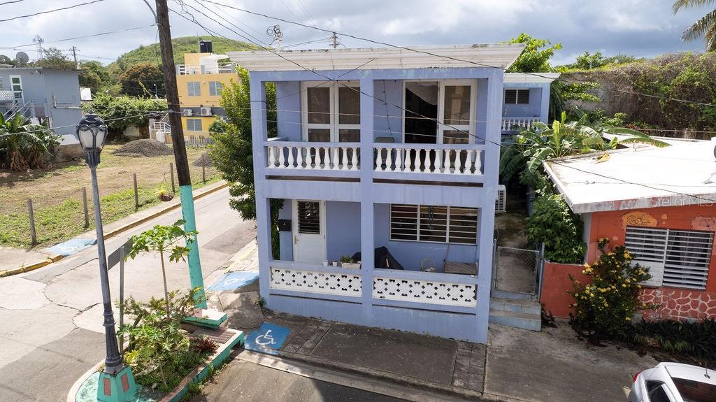 A two-story blue house with balconies and a ground-level patio sits along a street — 112 CALLE MUÑOZ RIVERA, VIEQUES, PR
