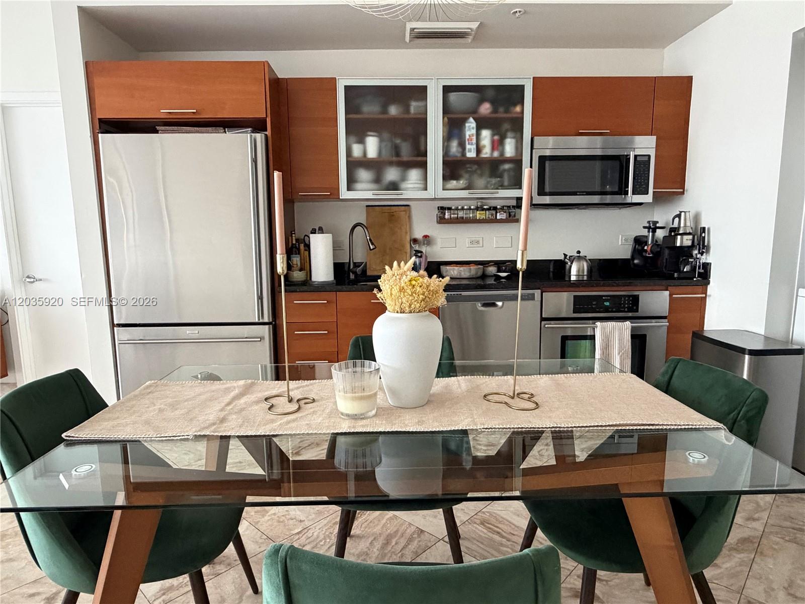 A kitchen features wood cabinets, stainless steel appliances, and a glass-top dining table with chairs — 3470 E Coast Ave # H1206, Miami FL 33137, MIAMI, FL