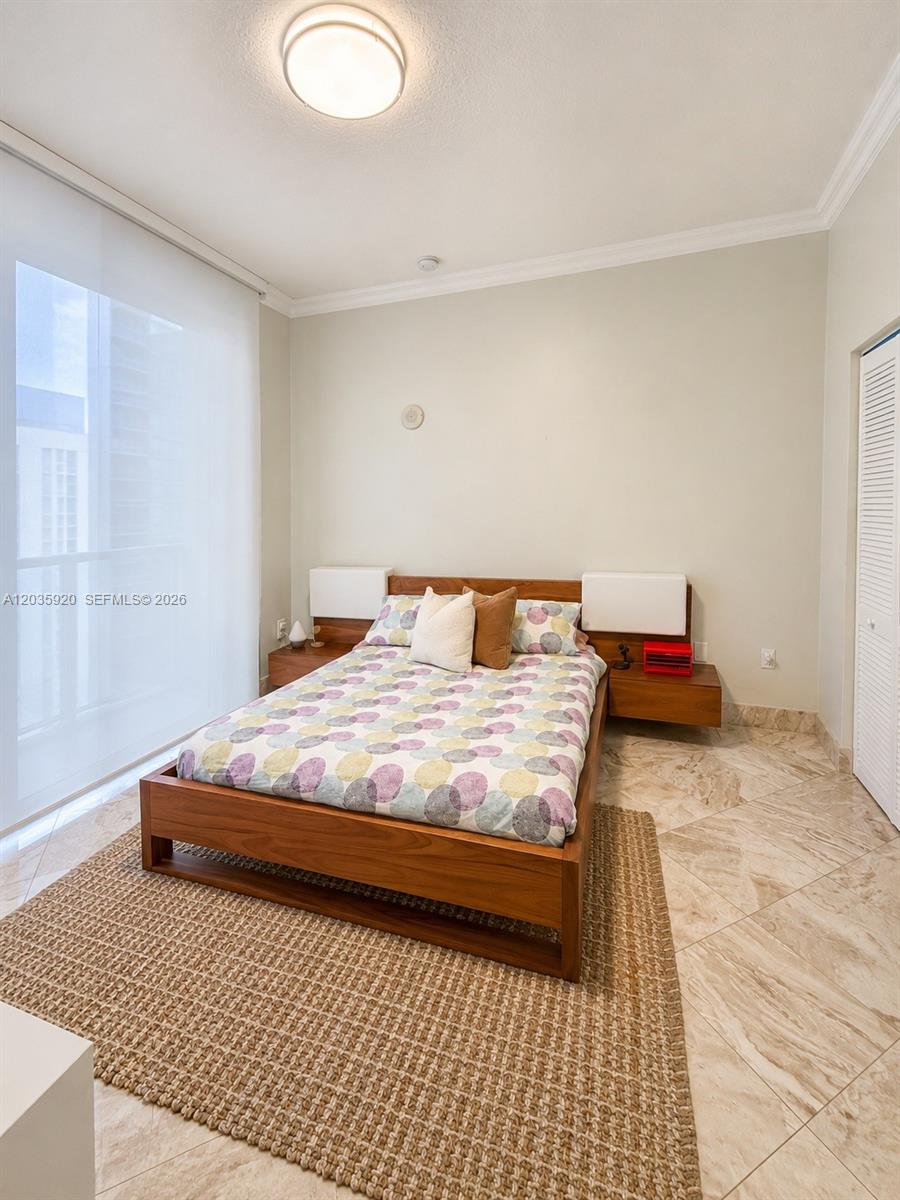A bedroom features a wooden bed frame, a patterned comforter, and a large area rug — 3470 E Coast Ave # H1206, Miami FL 33137, MIAMI, FL