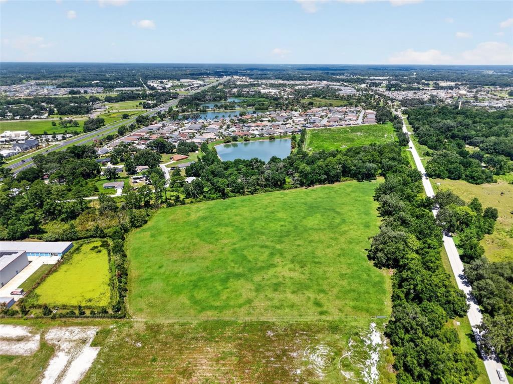 An aerial view shows a large, rectangular grassy lot bordered by trees and a road — 0 COUNTY ROAD 44 A, WILDWOOD, FL
