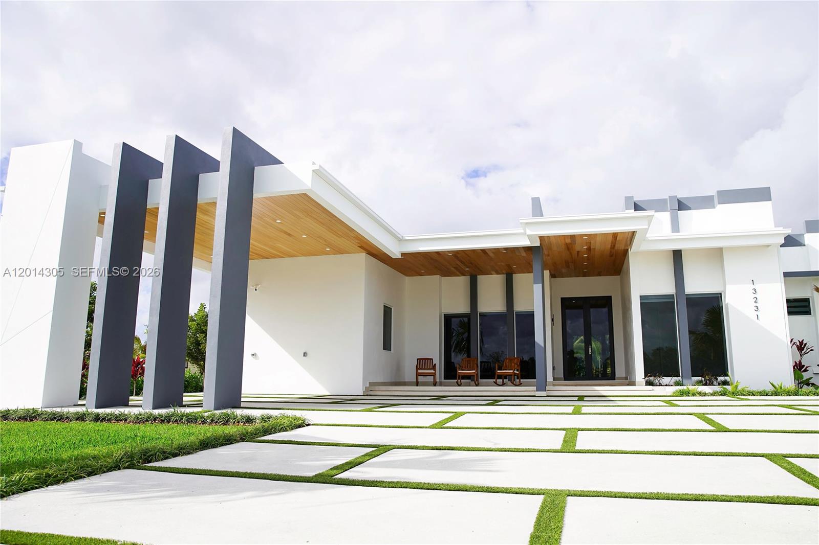 A modern white house features a large concrete paver driveway and a wood-paneled entryway — 13231 SW 220 ST, Miami FL 33170, MIAMI, FL