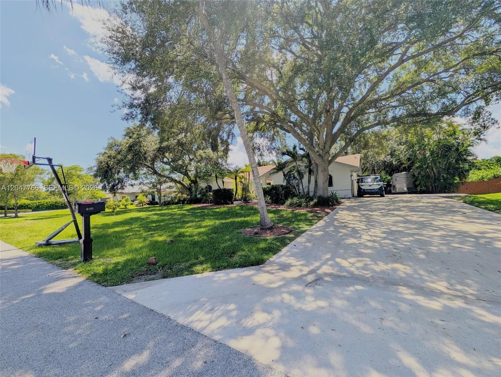 A driveway leads to a house with a large lawn, mature trees, and a basketball hoop — 5131 SW 201st Ter, Southwest Ranches FL 33332, SOUTHWEST RANCHES, FL