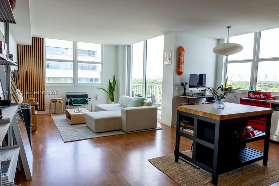 A modern living room and kitchen area features hardwood floors, floor-to-ceiling windows, and contemporary furniture — 3180 SW 22nd Ter # 1205, Miami FL 33145, MIAMI, FL