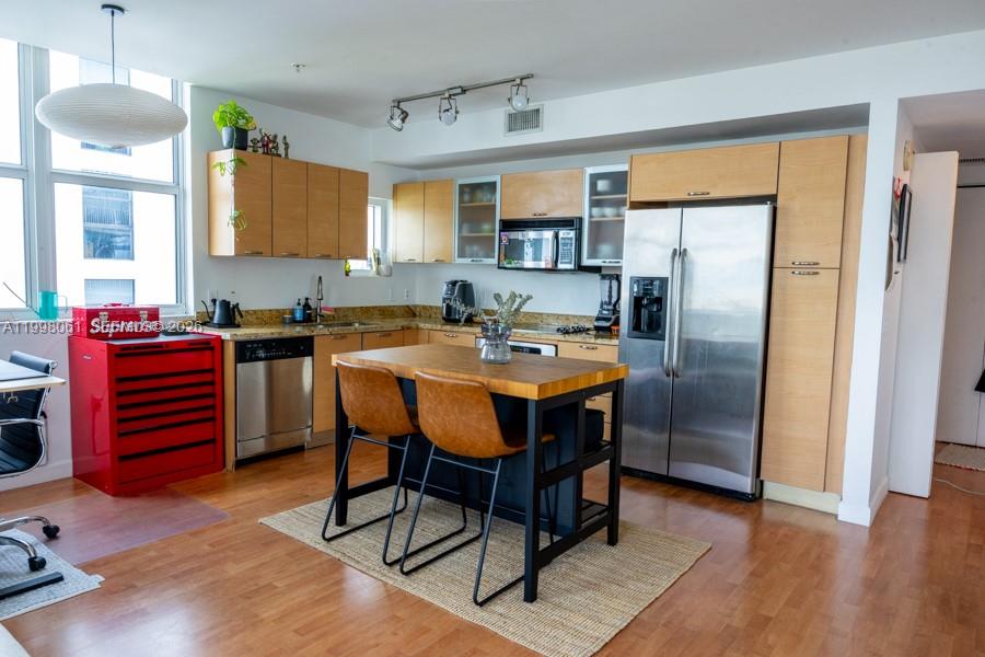 A kitchen features light wood cabinets, stainless steel appliances, and a central wooden island — 3180 SW 22nd Ter # 1205, Miami FL 33145, MIAMI, FL