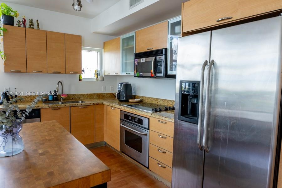 A kitchen features light wood cabinets, stainless steel appliances, and granite countertops — 3180 SW 22nd Ter # 1205, Miami FL 33145, MIAMI, FL