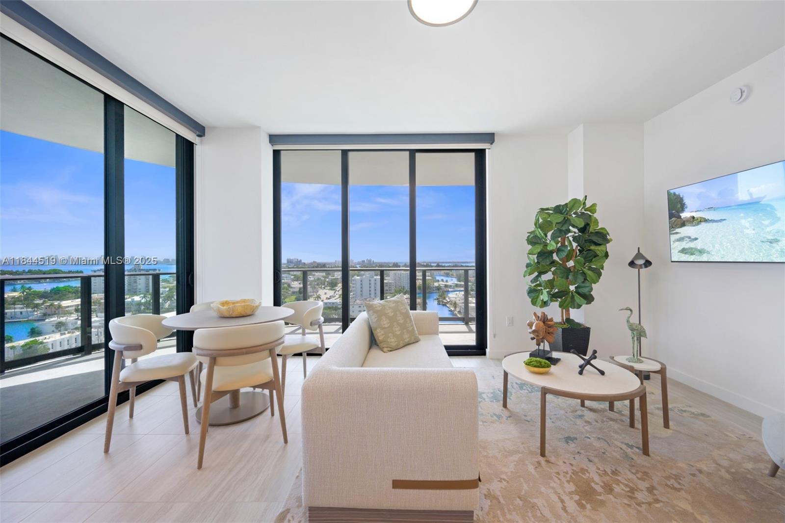 A bright living and dining area features floor-to-ceiling windows with a scenic water view — 580 72nd St # 1210, Miami Beach FL 33141, MIAMI BEACH, FL