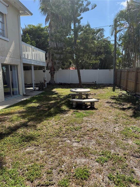 A backyard features a concrete table and bench set on a patchy lawn near a house — 1209 1ST STREET, INDIAN ROCKS BEACH, FL