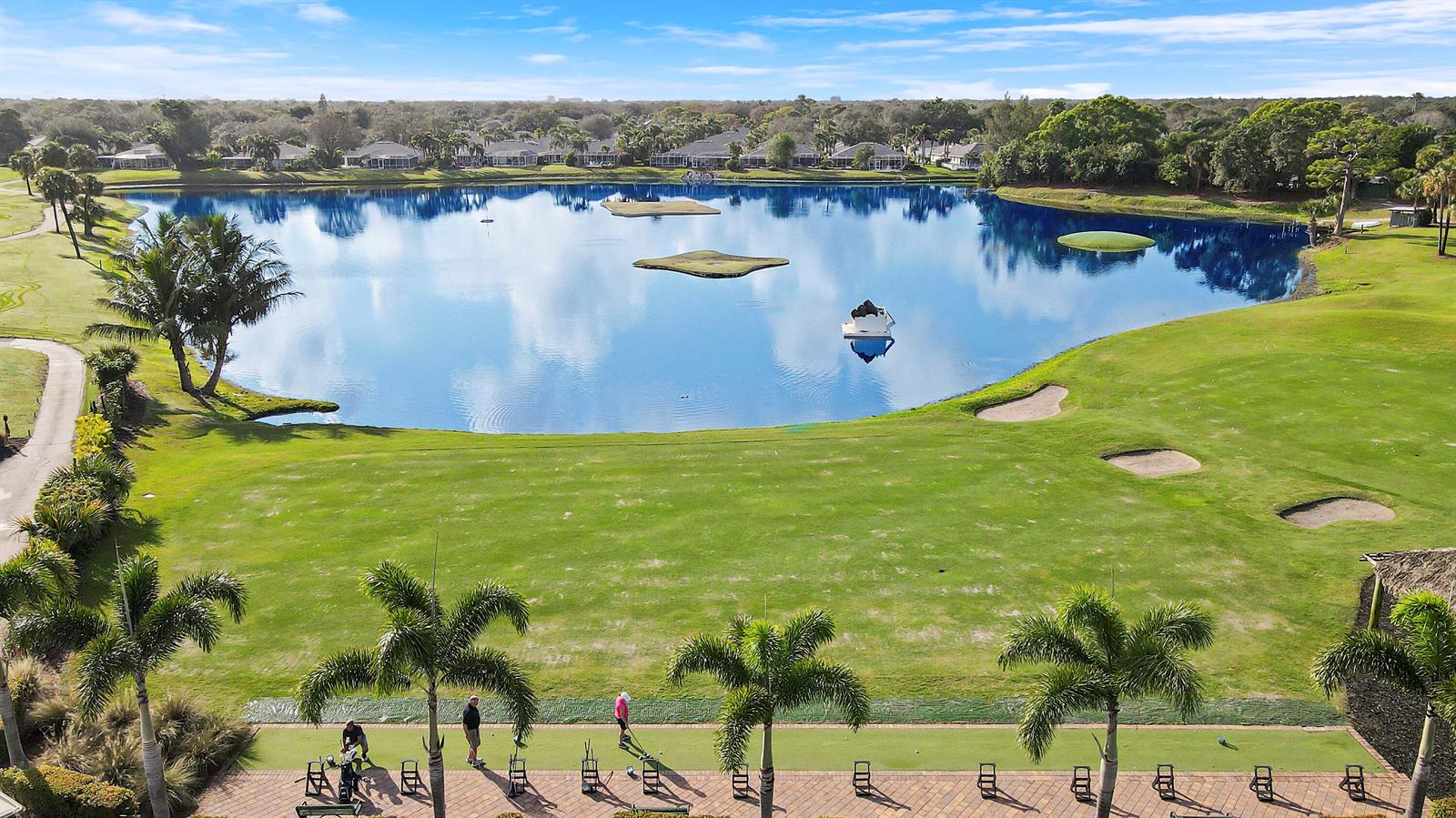 An aerial view shows a golf course driving range overlooking a large lake with islands — 1001 Pinecrest Circle # C, Jupiter FL 33458, JUPITER, FL