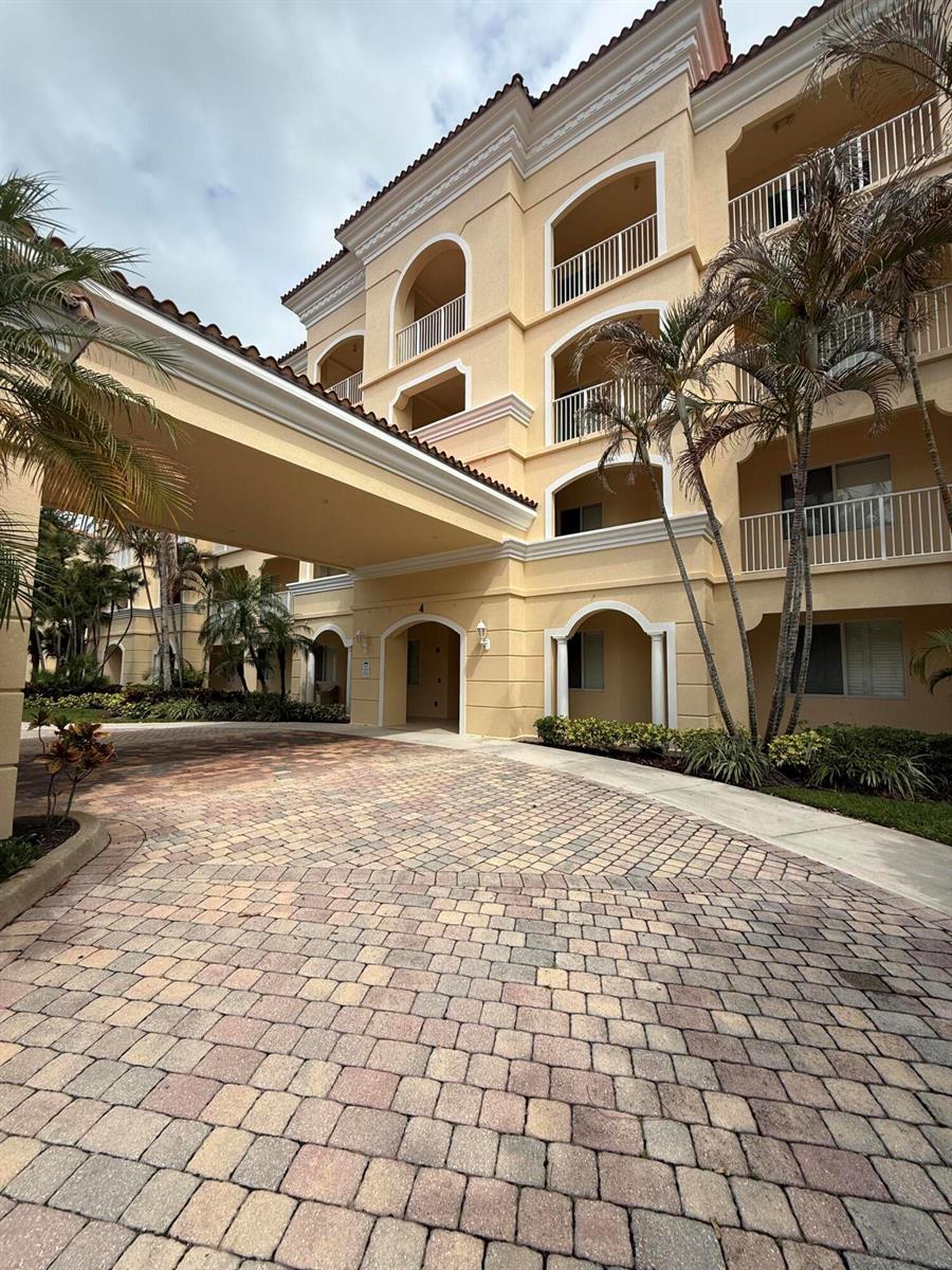 A multi-story tan stucco building features a covered entryway and a paved circular driveway — 4 Harbour Isle Drive E Unit 204, Fort Pierce FL 34949, FORT PIERCE, FL