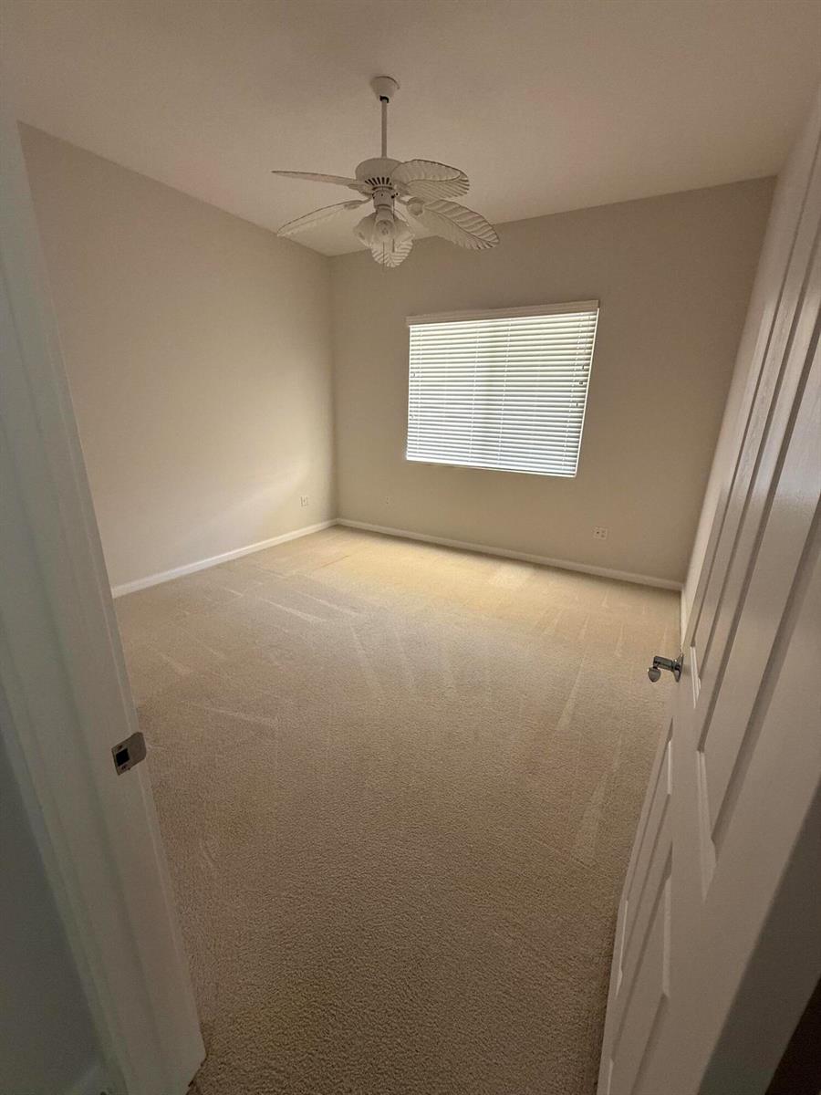 An empty bedroom features beige carpet, light-colored walls, a ceiling fan, and a window — 4 Harbour Isle Drive E Unit 204, Fort Pierce FL 34949, FORT PIERCE, FL