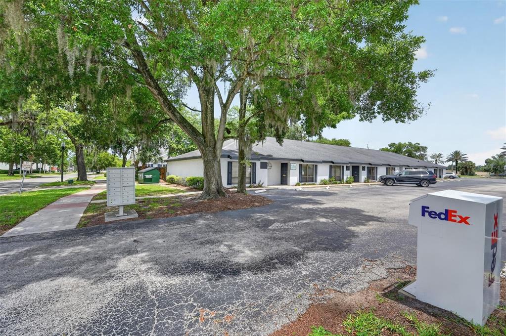 A single-story commercial building with a parking lot, a FedEx drop box, and large trees — 7 W MAIN STREET UNIT 12-14, APOPKA, FL