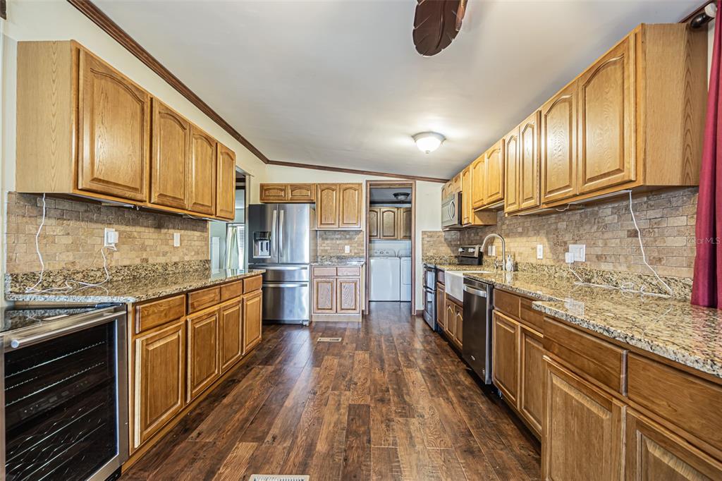 A galley kitchen features wood cabinets, granite countertops, stainless steel appliances, and wood-look flooring — 34445 COUNTRYSIDE DRIVE, WESLEY CHAPEL, FL